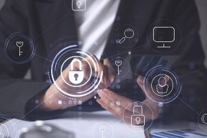 A close-up of a person's hands holding a smartphone and a pen, with various digital security icons, including a padlock and key, overlaid in soft focus, suggesting themes of cybersecurity and data protection.